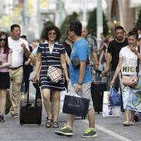 Charge it: A group of Chinese tourists carry shopping bags and suitcases in Tokyo. It's a small world, with no respect for islands