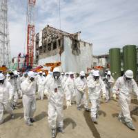 Danger zone: Members of the media and Tepco employees walk in front of the No. 4 reactor building at Fukushima No. 1 nuclear plant in May 2012. The plant was hit by a series of meltdowns following the Great East Japan Earthquake in 2011, and reportage on those meltdowns has been confusing to some in the public. | BLOOMBERG