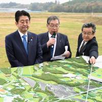 Prime Minister Shinzo Abe, on a visit Monday to Okuma, Fukushima Prefecture, listens to local officials describe their hopes for reconstruction. The town co-hosts the Fukushima No. 1 nuclear power plant. | KYODO