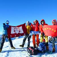 Students of Kobe University and China University of Geosciences display their school flags after becoming the first to conquer 6,330-meter-high Mount Tali, in Tibet, on Tuesday. | A TEAM OF KOBE UNIVERSITY AND CHINA UNIVERSITY OF GEOSCIENCES CLIMBERS/KYODO