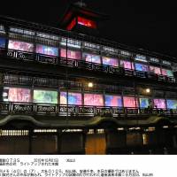 Dogo Onsen Honkan, a renowned hot spring bathhouse in Matsuyama, Ehime Prefecture, is illuminated Wednesday evening with works by photographer Mika Ninagawa printed on traditional shoji screens. The display began Thursday and runs through the end of February. | KYODO
