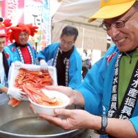 A Tottori Prefecture fisheries representative hands out soup garnished with expensive beni-zuwaigai crab meat in Osaka on Saturday. About 600 bowls were served up to promote Tottori, which is known for its crabs. | KYODO
