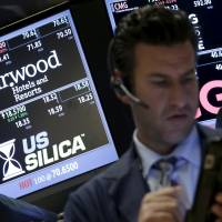 Traders stand by the post where the stock for Starwood Hotels | REUTERS
