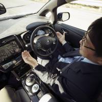 Nissan Motor Co. General Manager Tetsuya Iijima takes his hands off of the steering wheel of a self-driving prototype vehicle during a test drive in Tokyo on Tuesday. Prime Minister Shinzo Abe will ease regulations to allow self-driving cars to be tested on public roads. | AP