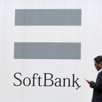 A man looks at his phone as he walks past a SoftBank advertisement in Tokyo last month. | REUTERS