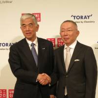 Uniqlo Co. CEO Tadashi Yanai (right) and Toray Industries Inc. President Akihiro Nikkaku shake hands after a news conference in Tokyo on Tuesday. | KAZUAKI NAGATA
