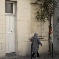 A woman walks by the house of the family of Belgian militant Abdelhamid Abaaoud in Molenbeek, Belgium, on Wednesday. The family homes of the suspected mastermind of the Paris attacks and one of the suicide bombers stand only a few blocks apart in the Belgian capital\'s Molenbeek neighborhood. | AP