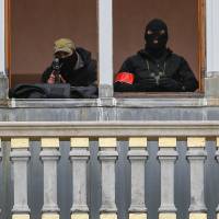 A Belgian police sniper and observer are seen on a balcony of a building in Brussels on Friday after security was tightened in the Belgian capital following the Nov. 13 terrorist attacks in Paris. | REUTERS
