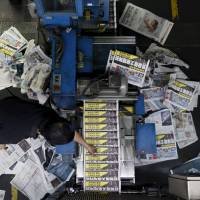 An employee takes a copy of the Apple Daily newspaper, published by Next Media Ltd., at the company\'s printing facility in Hong Kong on Thursday. The pro-democracy Apple Daily, which says it is hacked on an almost weekly basis, has tightened its email security software, and has its lawyers use couriers rather than email. | REUTERS