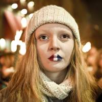 A girl with lips painted in French tricolor attends a vigil in memory of Paris attack victims in front of the French Embassy on Sunday in Copenhagen. | SCANPIX DENMARK / NILS MEILVANG / AFP-JIJI