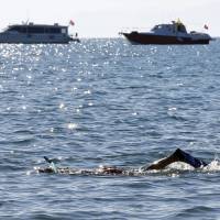 A man, with police and security boats in the background, swims near the summit zone ahead of the G-20 summit in Belek in the Mediterranean resort city of Antalya, Turkey, Saturday. | REUTERS