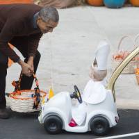 U.S. President Barack Obama greets a young child dressed as the pope and riding in a \"Popemobile\" as he hands out treats to children trick-or-treating for Halloween on the South Lawn of the White House in Washington Saturday. | AFP-JIJI