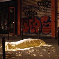 A dead victim covered by a blanket lies outside the Bataclan concert hall in Paris on Friday. | AP