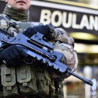 A French soldier stands guard in front of a bakery in the 20th district of Paris on Sunday, following a coordinated wave of attacks on Parisian nightspots claimed by the Islamic State group, which killed 130 people. | AFP-JIJI