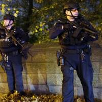 Heavily armed New York City police officers stand guard across the street from the French Consulate on New York\'s Fifth Avenue on Friday. Police in New York say they\'ve deployed extra units to crowded areas of the city \"out of an abundance of caution\" in the wake of the attacks in Paris. | AP