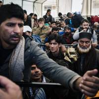 A man argues as he waits along with other migrants and refugees at a registration camp after crossing the Greek-Macedonian border near Gevgelija on Saturday. French authorities said a Syrian passport found near one of the Paris attack gunmen was for a man who arrived in Greece last month among purported refugees. | AFP-JIJI