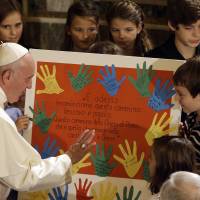 Pope Francis is presented with a gift during a visit to the Lutheran church in Rome, Sunday. Francis has condemned the Paris terror attacks, calling it \"blasphemy\" to use the name of God to justify \"the road of violence and of hatred.\" | AP