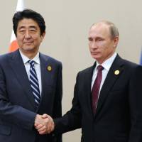 Prime Minister Shinzo Abe and Russian President Vladimir Putin shake hands prior to talks at the G-20 summit in Antalya, Turkey, on Monday. | AP