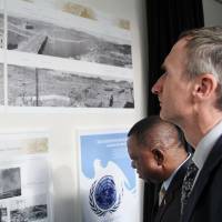 Diplomats at the U.N.\'s office in Vienna on Tuesday look at photographs showing parts of the cities of Hiroshima and Nagasaki shortly after the 1945 atomic bombings. The pictures are now on permanent display. | KYODO