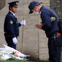 A man offers a prayer for victims of the Paris attacks in front of the French Embassy in Tokyo on Sunday as a police officer stands guard. | AFP-JIJI