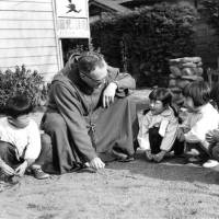 The Rev. Charles Brozat addresses children at play in this undated photograph. The former U.S. serviceman, decorated in the Pacific War, returned to Japan as a missionary and served there for 54 years. | SOCIETY OF ATONEMENT