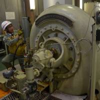 Takeshi Yajima of Chubu Electric Power Co. checks a water mill at the Miyashiro No. 1 power plant, the nation\'s oldest hydroelectric power plant, in Azumino, Nagano Prefecture. | CHUNICHI SHIMBUN