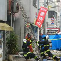 Firefighters try to rescue people in a three-story building in Miyakonojo, Miyazaki Prefecture, where a fire broke out and killed four people on Sunday. | KYODO