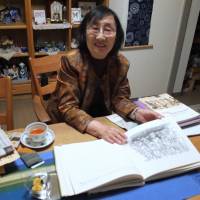 Michiko Nomura displays drawings by a Holocaust survivor during an interview in her home in Kawagoe, Saitama Prefecture, on Oct. 26. | MAGDALENA OSUMI