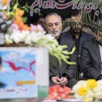 Former Iranian President Mahmoud Ahmadinejad (right) and Head of the Iranian Atomic Energy Organization Ali Akbar Salehi sit next to the coffin of Amin Karimi, a member of the Iranian Revolutionary Guards who was killed in Syria, during his funeral in Tehran Oct. 28. Salehi said Monday in Tokyo that Iran is taking its nuclear centrifuges offline. | TIMA/ RAHEB HOMAVANDI / REUTERS