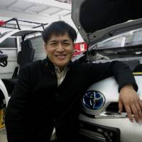 Robot Taxi Inc. Chairman Hisashi Taniguchi poses with modified cars capable of self-driving at ZMP Inc.\'s garage in Tokyo. | KAZUAKI NAGATA