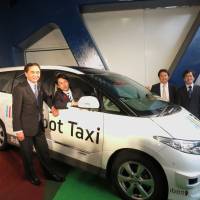 Liberal Democratic Party lawmaker Shinjiro Koizumi sits in a self-driving car developed by Robot Taxi Inc. at Yokohama Stadium in October as (from left) Kanagawa Gov. Yuji Kuroiwa, Robot Taxi President Hiroshi Nakajima and Chairman Hisashi Taniguchi look on. | KAZUAKI NAGATA
