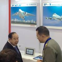 Thai Deputy Prime Minister and Defense Minister Gen. Prawit Wongsuwan (left) is briefed at a booth operated by Kawasaki Heavy Industries during a defense-equipment trade show in Bangkok on Monday. | KYODO