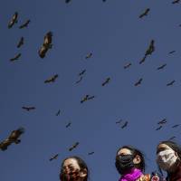 Vultures soar over mourners gathering for a sky burial at the same location, atop a hill near the Larung Wuming Buddhist Institute. | REUTERS