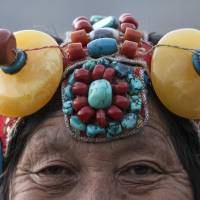 An ethnic Tibetan woman from the ancient Kham region, which now lies mostly in the Tibet Autonomous Region and Sichuan, wears traditional jewelry made of amber and stone. | REUTERS