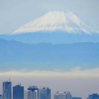 Mount Fuji fills the horizon behind skyscrapers in Shinjuku Ward, Tokyo, partially hidden by fog Tuesday morning. | KYODO