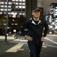 Toshihiro Matsui, chief health officer of Daiwa Securities Group Inc., warms up before going for a run near the Imperial Palace in Tokyo on Dec. 1. The Tokyo-based firm appointed Matsui to oversee programs that give incentives for employees to exercise and leave work on time. | BLOOMBERG