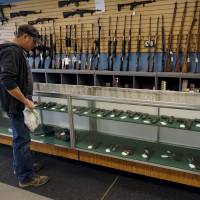 A customer looks over weapons for sale at the Pony Express Firearms shop in Parker, Colorado, Monday. Many Americans are stocking up on weapons after the country\'s worst mass shooting in three years. Gun retailers are reporting surging sales, with customers saying they want to keep handguns and rifles at hand for self-defense in the event of another attack. | REUTERS