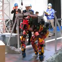 Robot HRP-2 Kai (left) demonstrates walking on a narrow path, while Jaxon shows that it can duck while moving. The humanoids were on display at the International Robot Exhibition 2015 in Tokyo\'s Koto Ward. Both are designed for work following disasters and were demonstrated at a booth operated by New Energy and Industrial Technology Development Organization. | KAZUAKI NAGATA