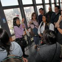 A tour guide speaks to visitors inside the Tokyo Tower during a sightseeing tour operated by Hato Bus Co. in Toyko on Nov. 5. | BLOOMBERG