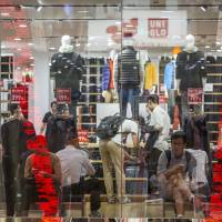 Customers sit inside the Fast Retailing Co. flagship Uniqlo store in Shanghai, China, in September. Uniqlo will devote an entire floor at its six-story China flagship store in central Shanghai to products co-designed with Disney. | BLOOMBERG