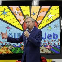 Republican presidential candidate former Florida Gov. Jeb Bush takes part in an event at Art Basel where his painting was unveiled by Miami artist Romero Britto  (left) as his wife, Columba (right) look on Saturday in Miami. | AP