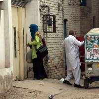 An unidentified woman and elderly man leave the house of Gulzar Ahmed Malik, the father of female U.S. shooter Tashfeen Malik, after Pakistani investigators examined the house in Multan on Sunday. | AFP-JIJI