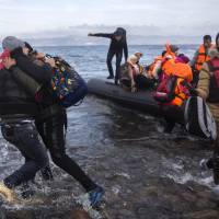 Migrants and refugees react as they arrive on a dinghy from the Turkish coast to the northeastern Greek island of Lesbos on Wednesday. Greek authorities said at the southeastern islet of Farmakonissi a number of people have died and others are missing after a boat carrying migrants sank in the Aegean Sea. | AP