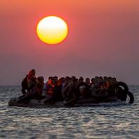 Migrants on a dinghy arrive at the southeastern island of Kos, Greece, after crossing from Turkey in August. The Italian coast guard said Thursday some 2,000 migrants have been rescued in the Mediterranean while bound for Italy in recent days. | AP