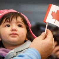 An arriving Syrian refugee is carried by her father at Pearson Toronto International Airport in Mississauga, Ontario, on Friday. | REUTERS