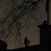 A U.S. Secret Service countersniper stands on the roof of the White House at sunrise Sunday in Washington. President Barack Obama will address the nation from the Oval Office on Sunday night about the steps the government is taking to fulfill his highest priority: Keeping the American people safe. | AP