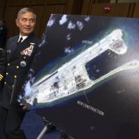 Adm. Harry B. Harris, Jr., commander of U.S. Pacific Command, walks past a photograph showing an island that China is building on the Fiery Cross Reef in the South China Sea, as he prepares to testify on Capitol Hill in Washington before the Senate Armed Services Committee in September. | AP