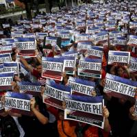 Activists hold up signs that read, \"Hands Off PH!\" during a protest over the South China Sea disputes, outside the Chinese Consulate in Makati City, Metro Manila in June. | REUTERS