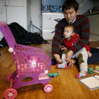 Chung Sang-hoon adjusts the clothes of his son at his apartment in Seoul on Dec. 14. | REUTERS