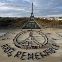 Hundreds of environmentalists arrange their bodies to form a message of hope and peace in front of the Eiffel Tower in Paris on Sunday, as the World Climate Change Conference 2015 continued at Le Bourget, near the French capital. | REUTERS